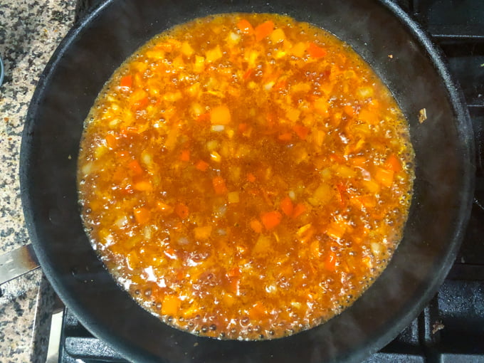 pan on stove with onions, peppers and cooking liquid