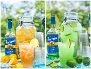 Spiked Iced tea and Margarita punch in large containers with Torani bottles, cups and sliced fruit outside