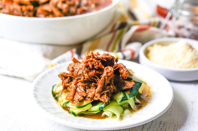 white plate with zucchini noodles with Instant Pot shredded beef on top 