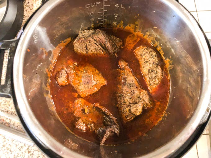 instant pot container with cooked Italian beef chunks and sauce