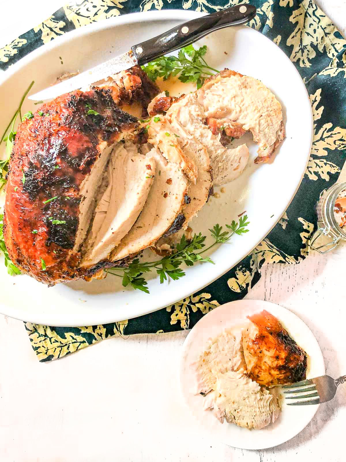 A platter and plate with carved air fryer turkey breast.