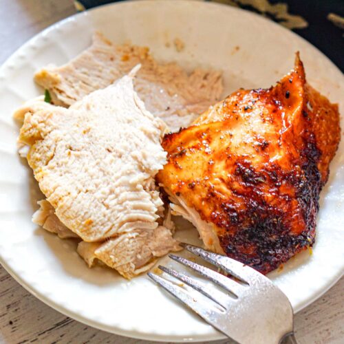 A white plate with serving of carved air fryer turkey breast.