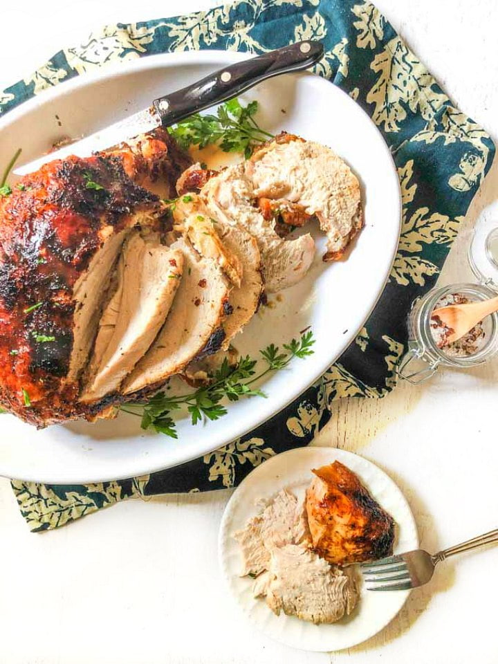 white plate and white platter with a roasted turkey and fork