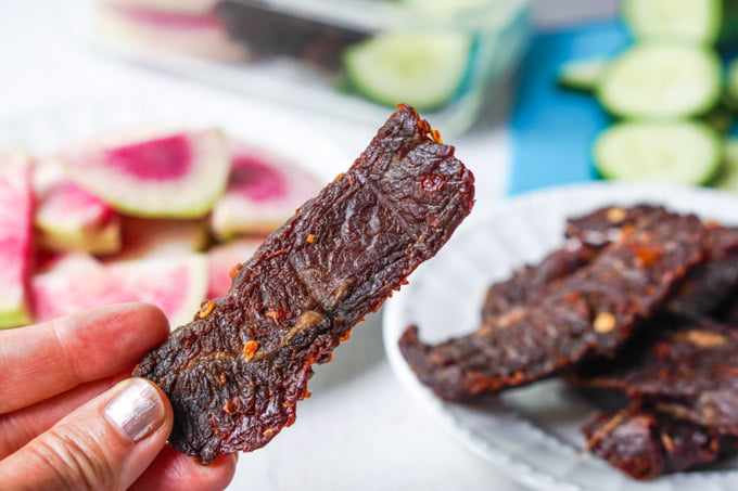hand holding a piece of low carb smoked beef jerky