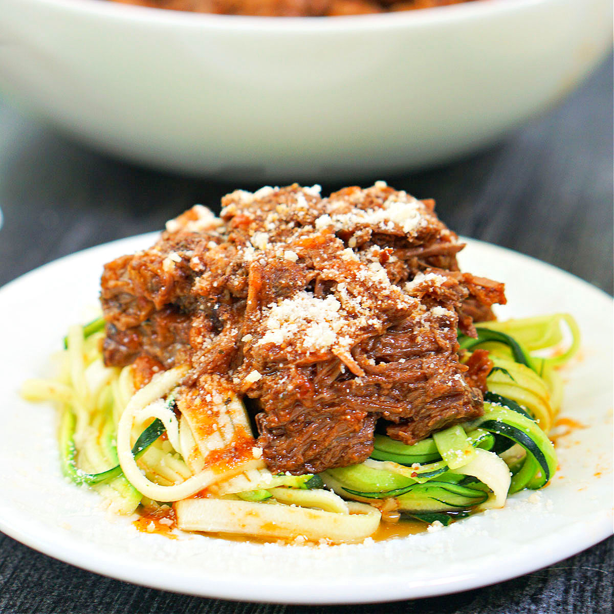 closeup of a plate fo zucchini noodles topped with shredded beef and cheese