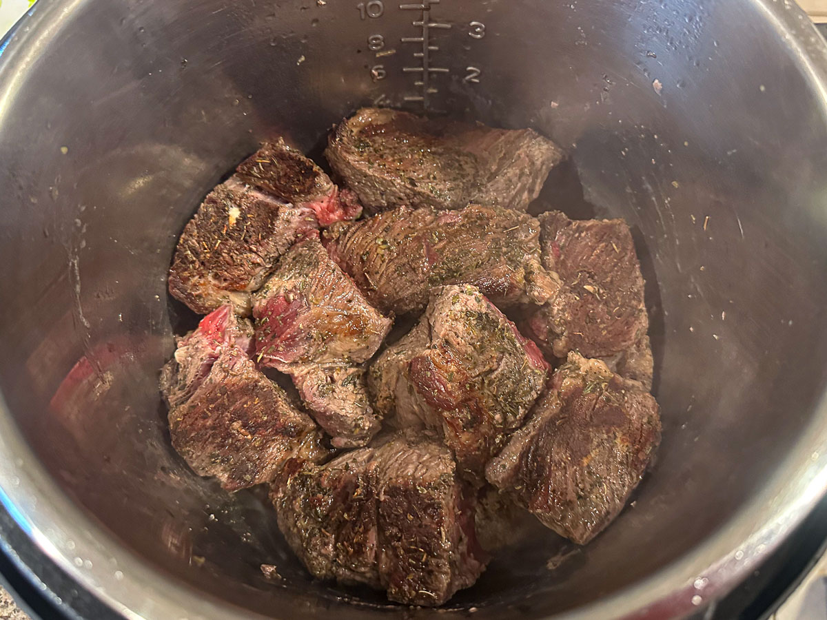 instant pot with browned chunks of beef