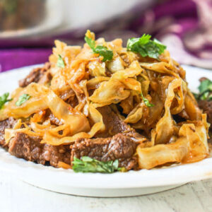White plate with a serving of beef and cabbage stir fry dish.