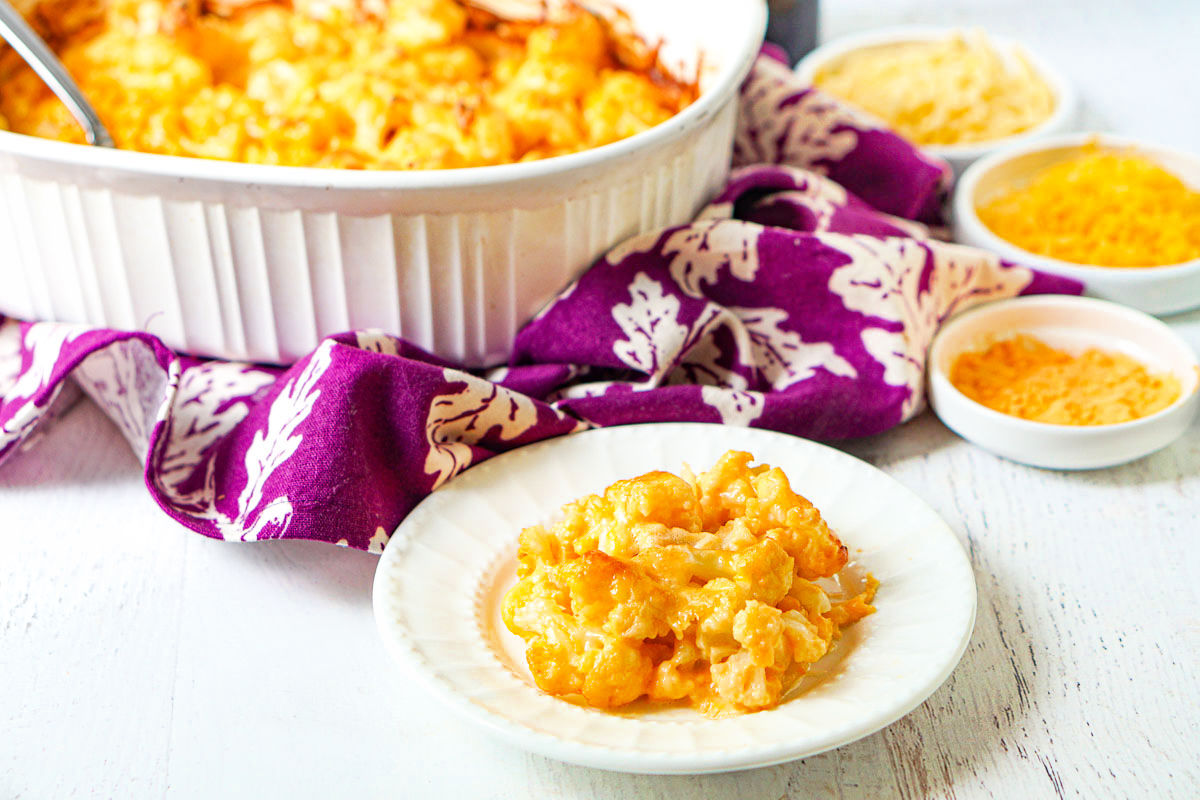 plate with cheesy cauli Mac and cheese with baking dish in background with various cheeses