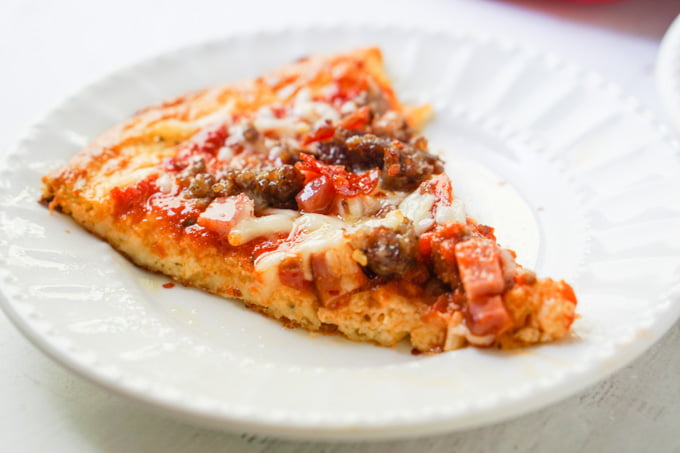 piece of meat lover's low carb pizza on white plate 