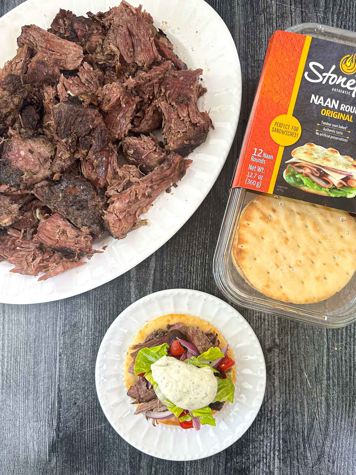 aerial view of a platter of Greek lamb and plate with a gyro and naan bread