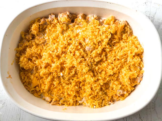 baking dish of uncooked casserole and cheese on top