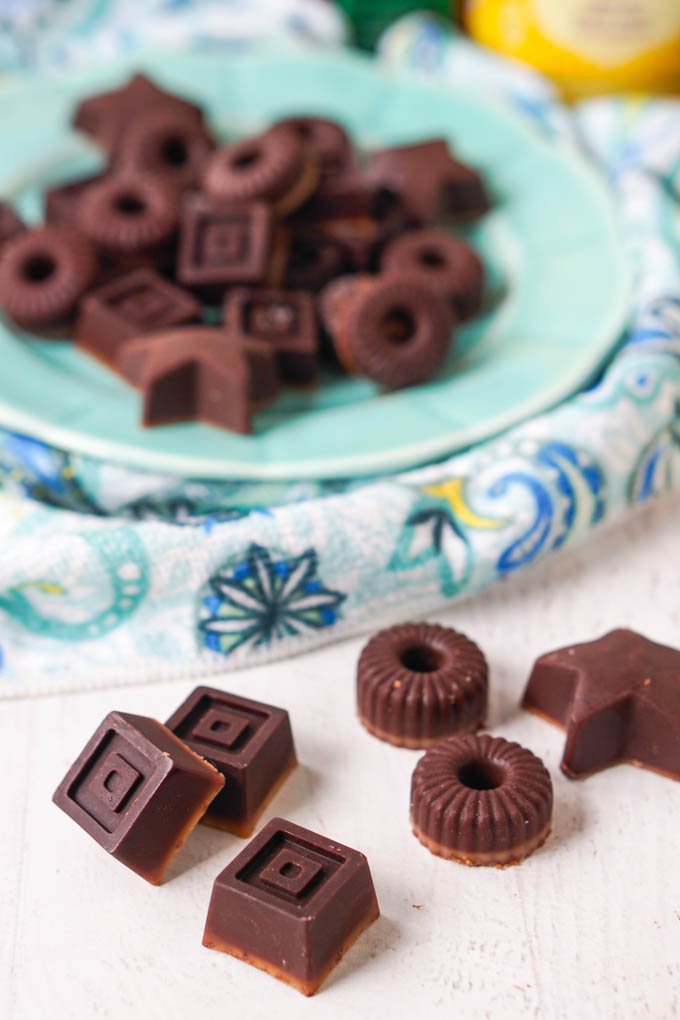 square, round and star chocolate candies with a blue plate in back and tea towel