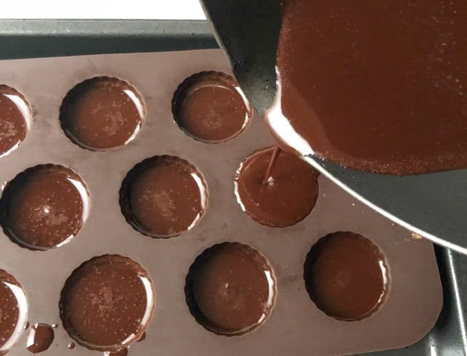 chocolate being poured from pan to candy mold