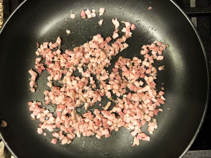 diced pancetta being sautéed in a skillet