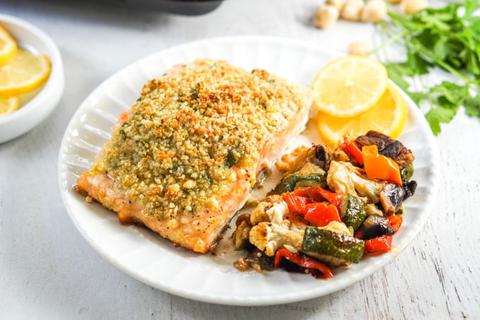 piece of nut crusted salmon and roasted vegetable on a white plate