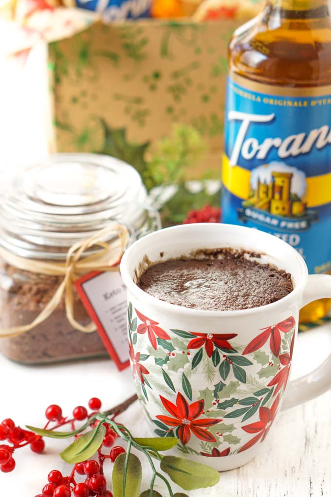 a poinsettia mug with a chocolate keto mug cake in it and a sprig of fake berries