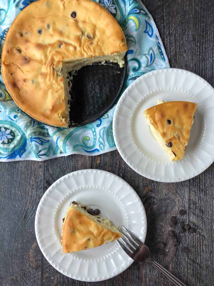 2 white plates with slices of low carb cheesecake and the rest of the cake on a blue tea towel