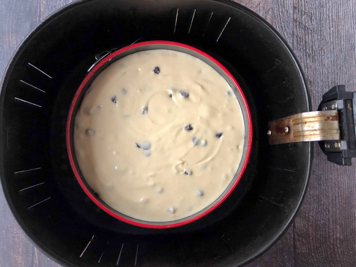 unbaked cheesecake in red springform pan in an air fryer basket