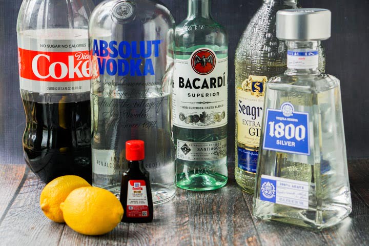 bottles of liquor and Diet Coke along with lemons and orange extract bottle to make keto Long Island ice tea