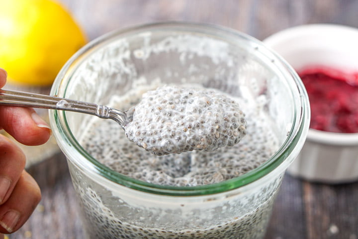 a spoonful of chia pudding made with almond milk with a berry sauce in background