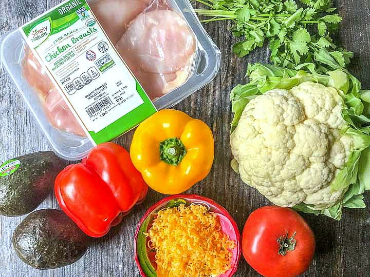 Fresh ingredients from Aldi for a keto burrito bowl: chicken, avocados, peppers, tomato, cauliflower, cilantro, and cheese