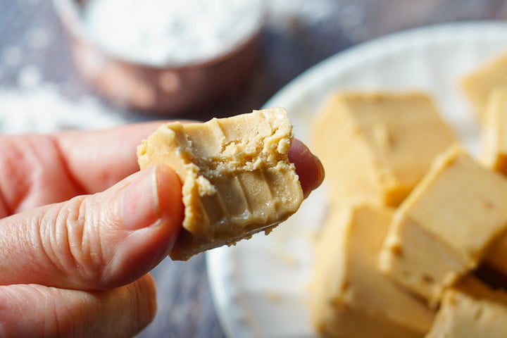 fingers holding a piece of the keto peanut butter fudge with a bite taken out