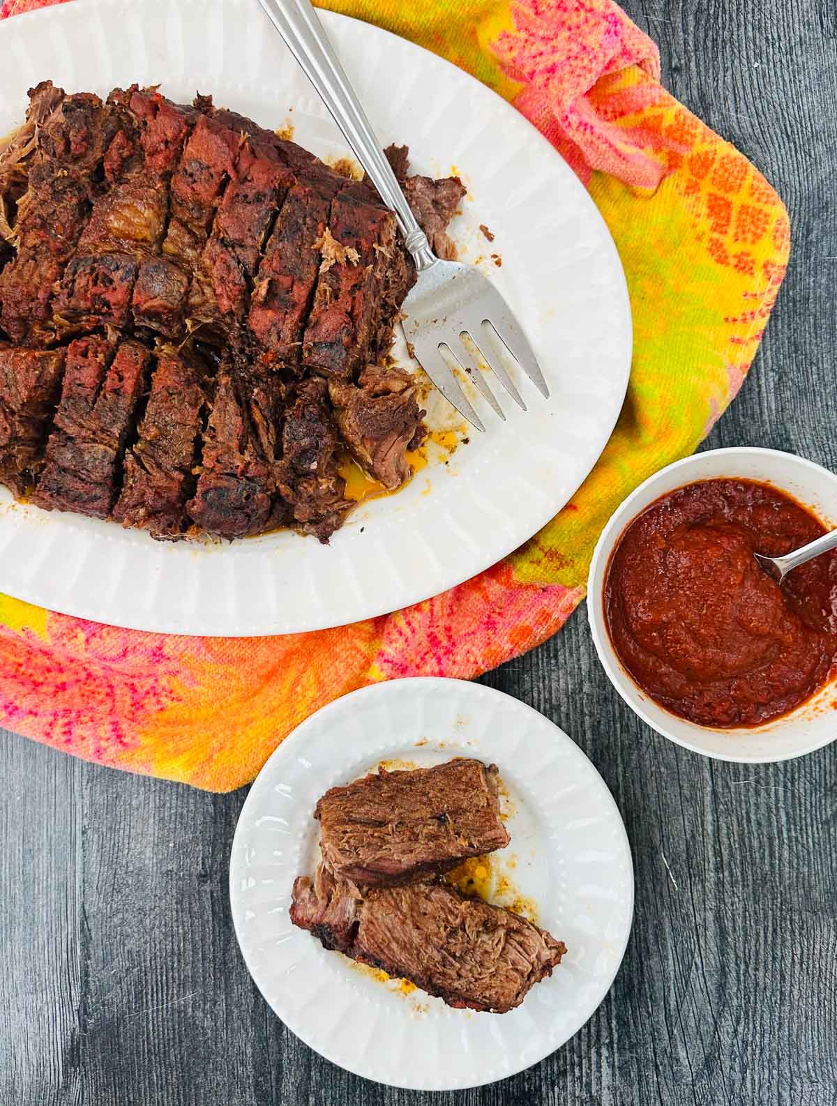 aerial view of a platter and plate with slow cooker beef roast and bbq sauce