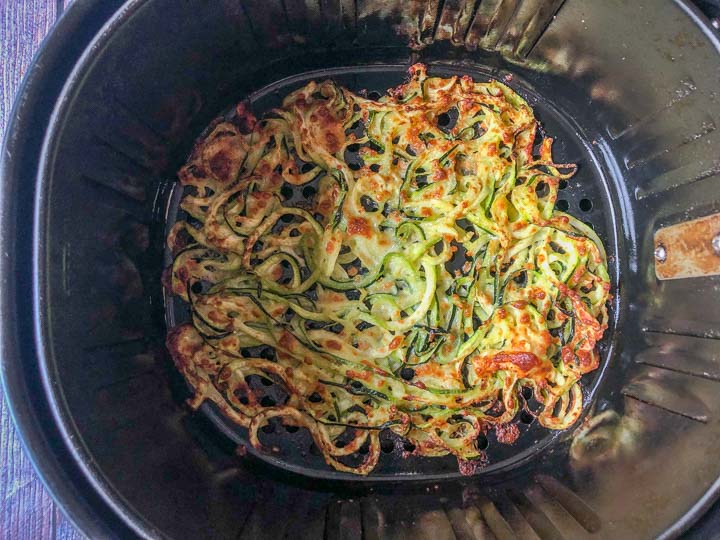 baked keto cheesy zucchini noodles in a the basket of an air fryer