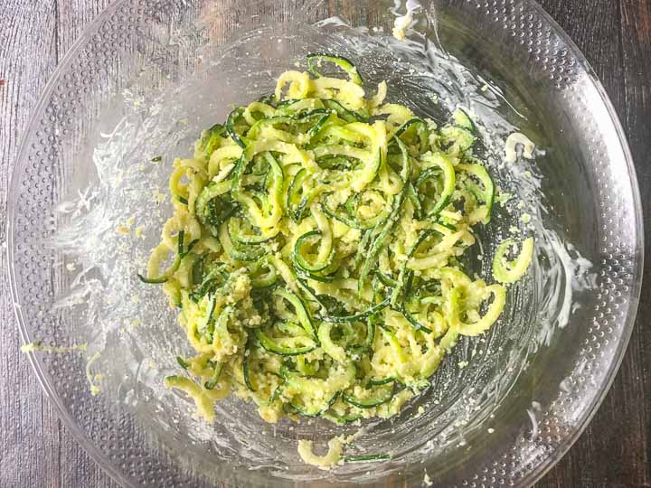 cheesy zucchini noodles in a glass mixing bowl