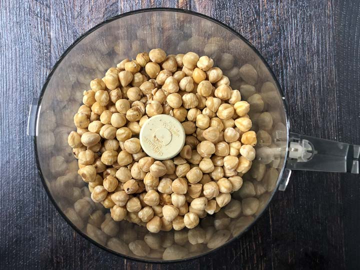 food processor bowl with roasted hazelnuts in it