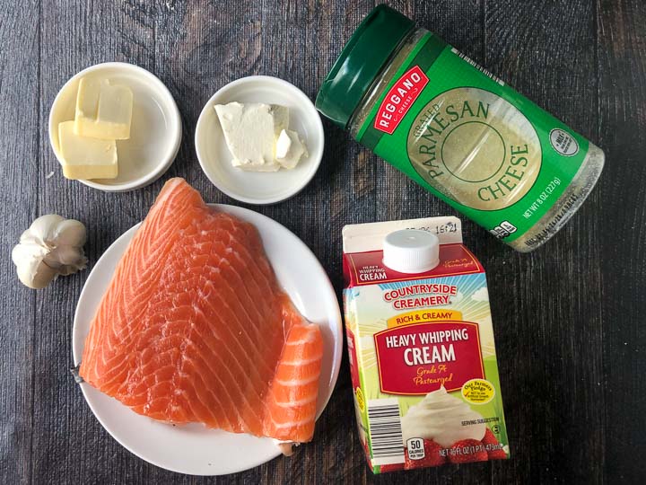 ingredients to make low carb salmon alfredo: garlic cloves, salmon, butter, cream cheese, cream and parmesan cheese