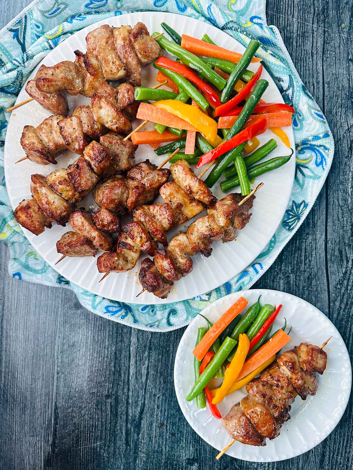 aerial view of white plate with keto pork bites on skewers and julienne vegetables