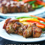 white plate with keto pork bites on skewers and julienne vegetables and text
