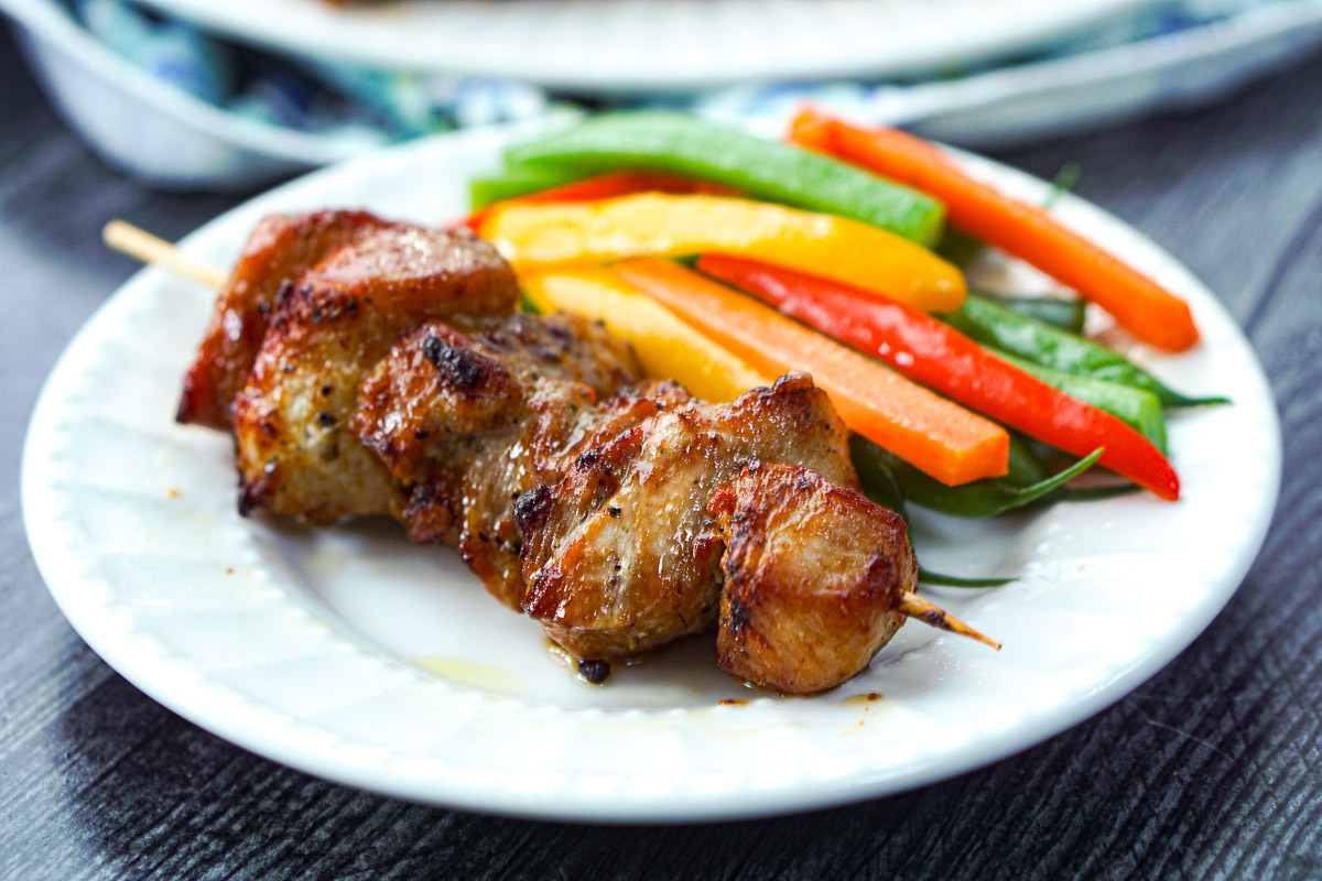 closeup of a plate with a pork skewer made in air fryer and some vegetables