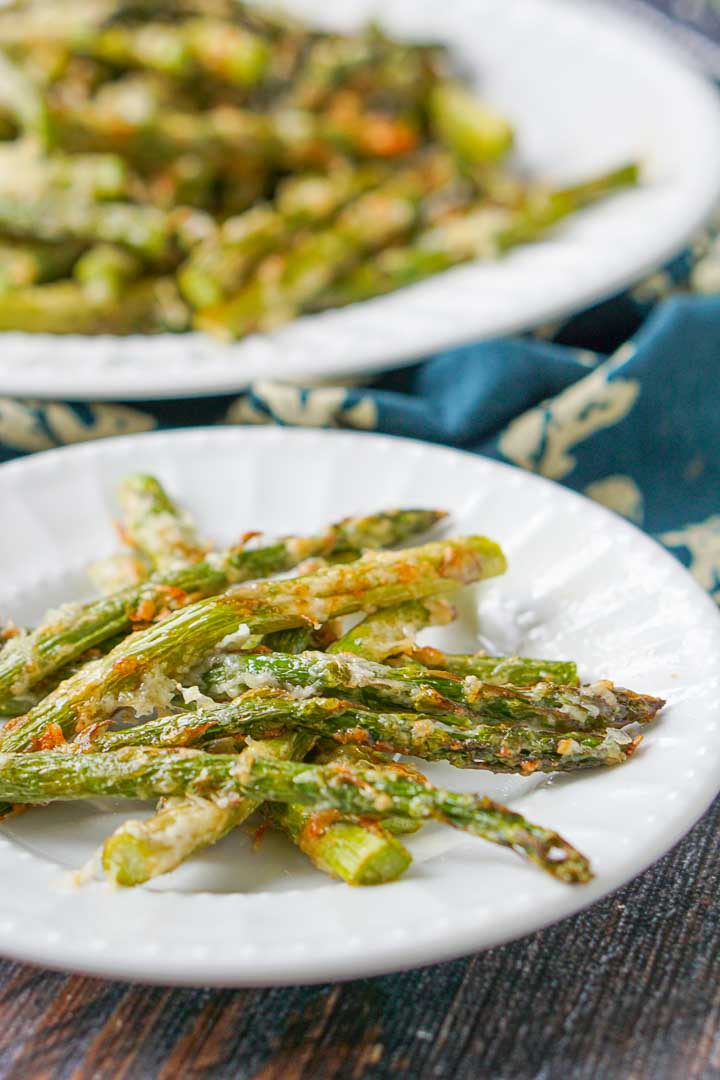 close up of a white plate with low carb asiago asparagus fries  and another plate in the background