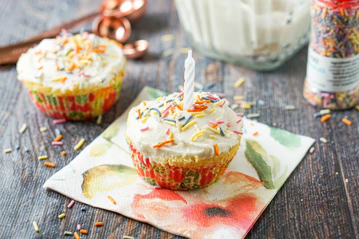 a microwave keto cupcake with a candle and sprinkles and floral napkin