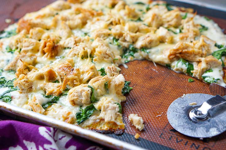 cookie sheet with keto chicken alfredo pizza with cauliflower crust and a pizza cutter