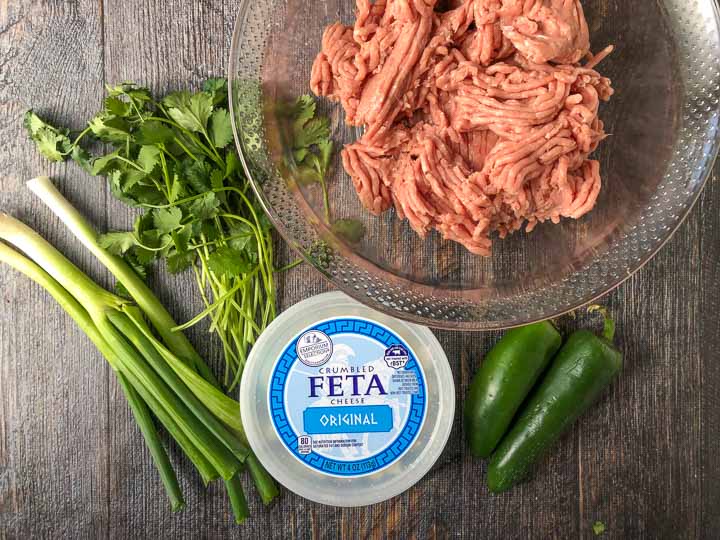 ingredients to make feta & cilantro turkey burgers: green onions, cilantro, raw ground turkey, jalapeno peppers and feta