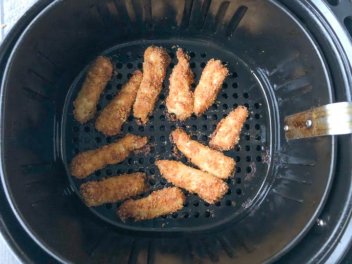 keto fish sticks in the basket of an air fryer that are baked