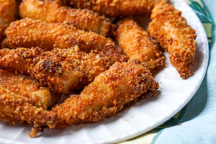 closeup of a white plate of crunchy low carb fish sticks made in the air fryer