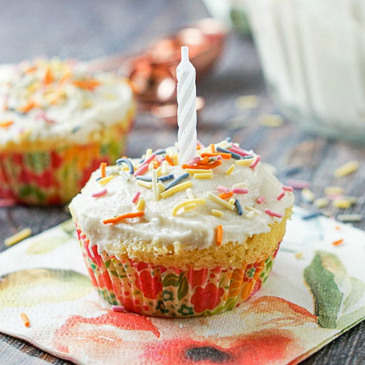 a microwave keto cupcake with a candle and sprinkles and floral napkin