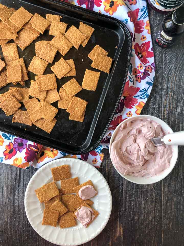 low carb peanut crackers on cookie sheet with a bowl of keto berry cream cheese spread