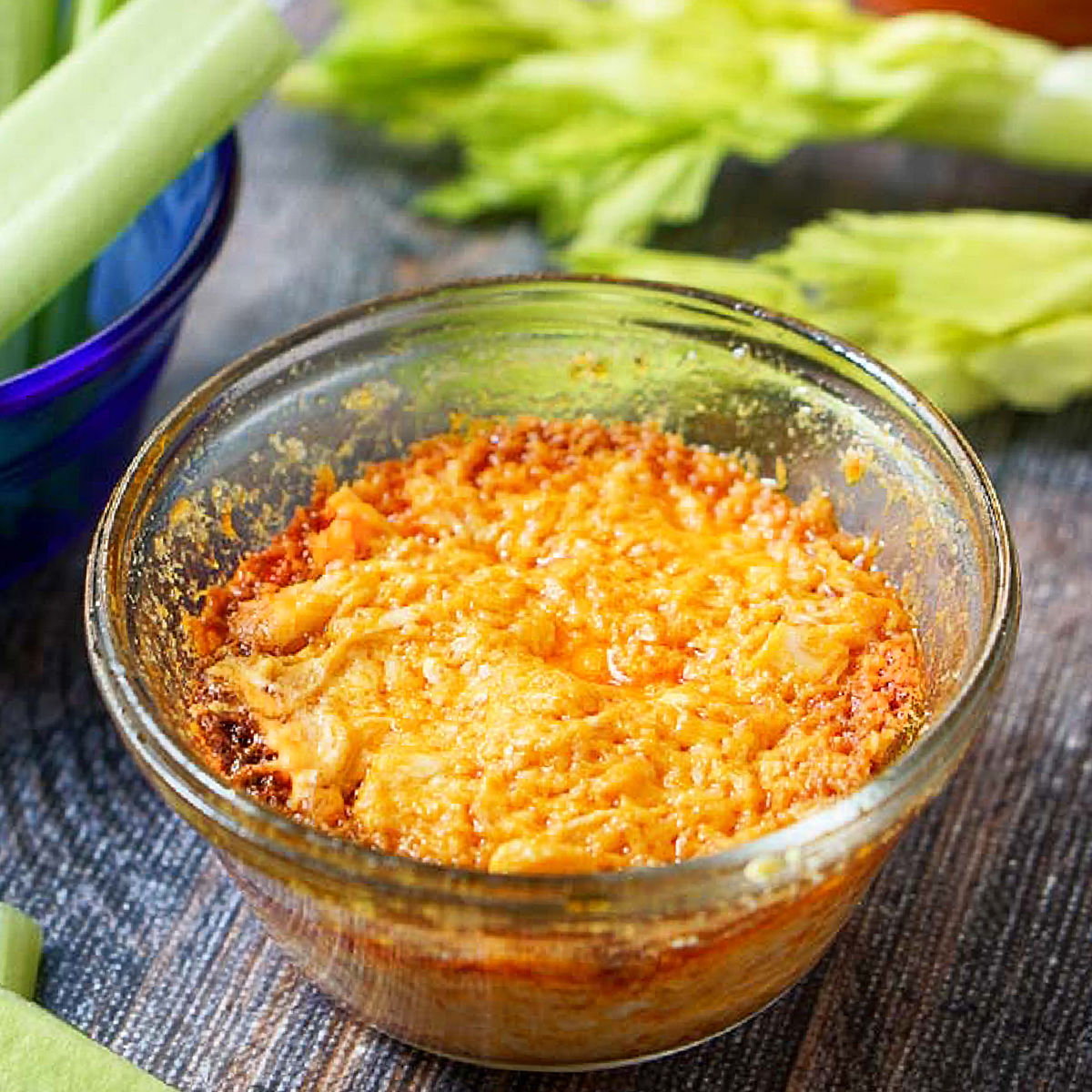 closeup of a glass container with keto buffalo chicken dip and celery in background