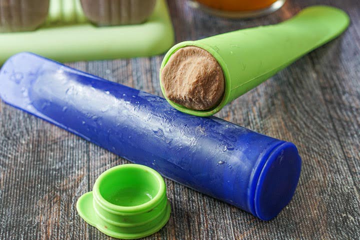 blue and green silicone push up molds with the chocolate pudding pops inside.