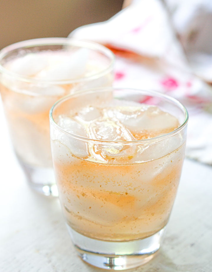 closeup of 2 glasses with ice and peach cocktail