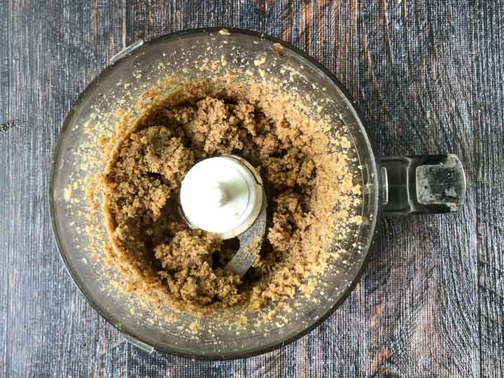 food processor bowl with crushed pecans and walnuts
