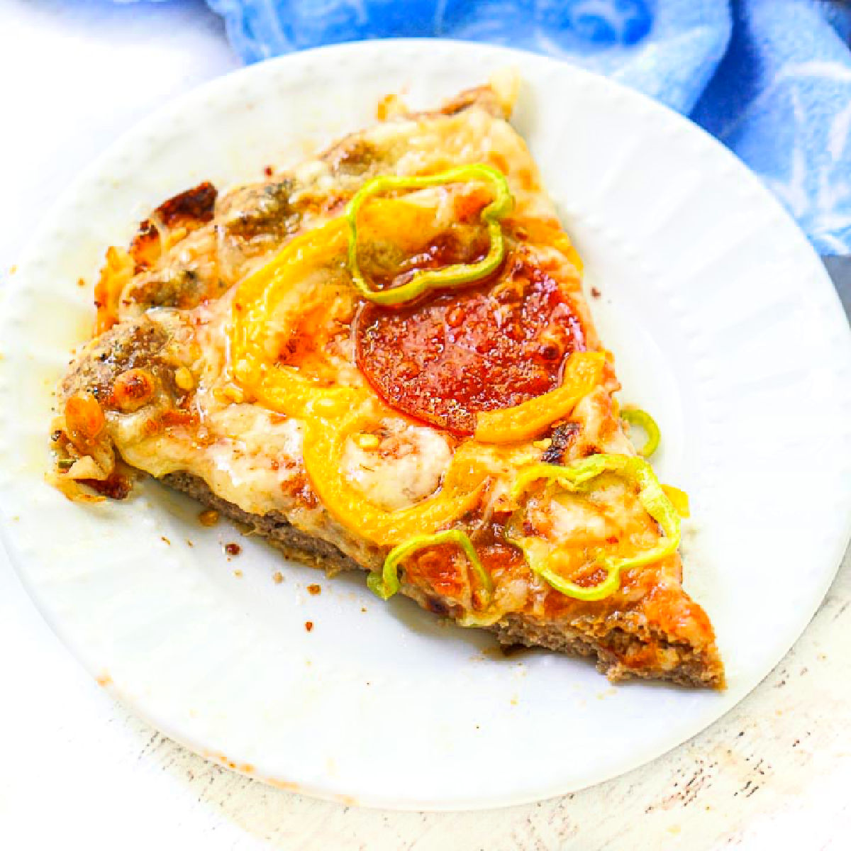 white plate with a piece of keto ground turkey crust pizza