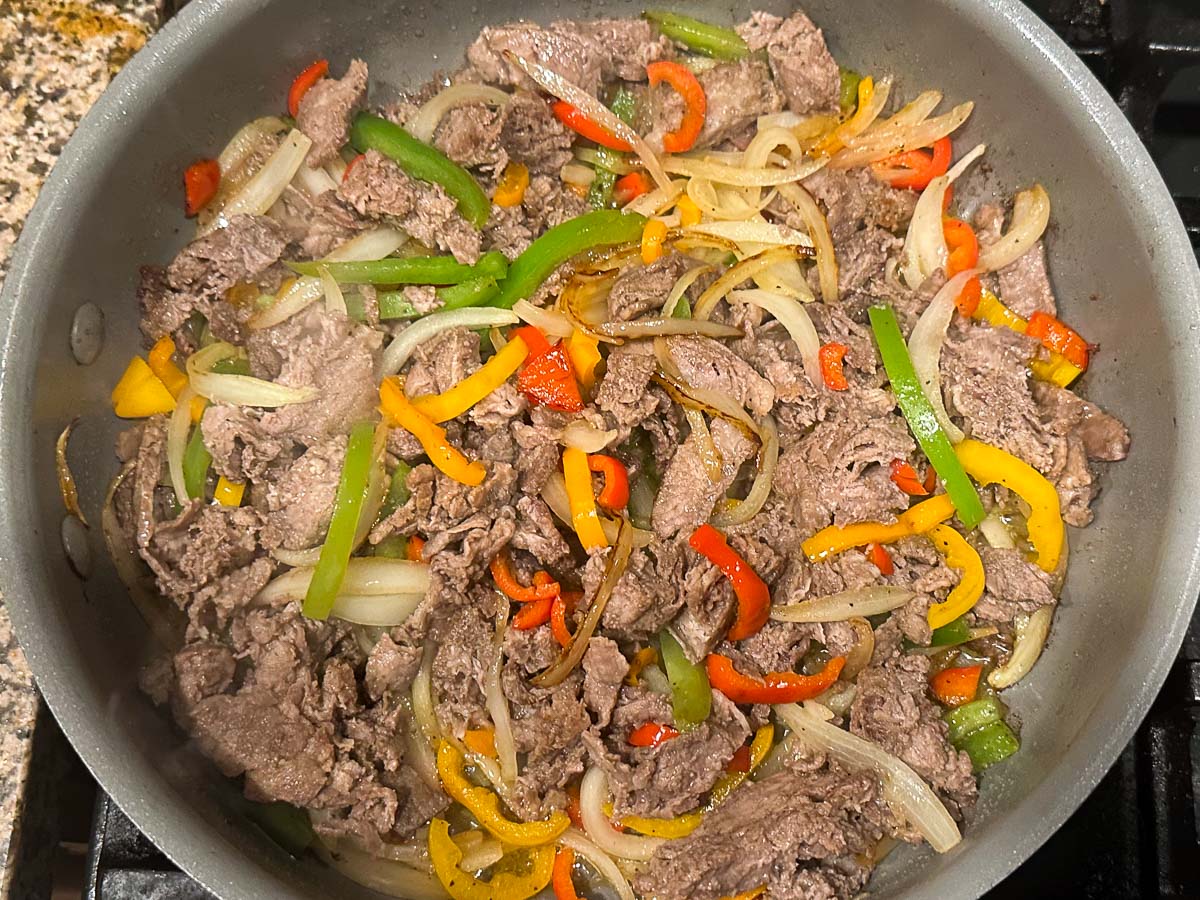 skillet with sautéed steak, onions and peppers