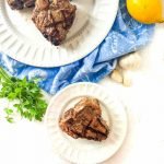 white plates with keto Greek lamb chops with lemons and blue towel and text overlay