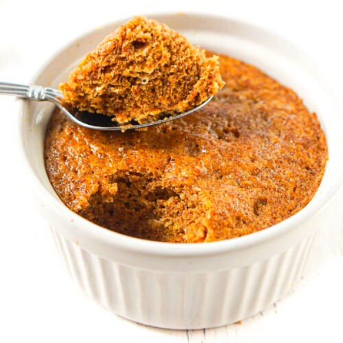 white ramekin with a healthy pumpkin mug cake and a spoonful of it